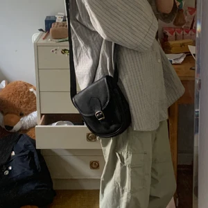 Axelremsväska-svart - Säljer denna gamla axelremsväska då den inte kommer till användning. Som det syns på andra bilden är den trasig vid knappen men detta försvårar inte användningen och syns även inte🫶