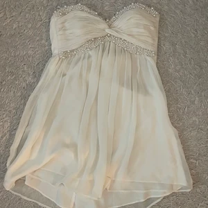 Vit klänning - Jättefin benvit klänning med pärlor som passar perfekt till t.ex student💗🤍 Säljer då den inte passade! Utöver dragkedjan som är någpt seg att dra upp är den i toppen skick! Påse med extra pärlor ingår