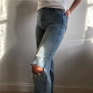 Ett par blåa högmidjade jeans med slitningar på knäna, köpta här på Plick men kommer från Zara. Inga slitningar eller fläckar.  (Lånad bild)  Säljer för 200 kr inkl frakt. 
