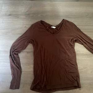 En brun tröja med v formad hals i stretchiga och skönt material vilket gör att den skulle kunna passa upp till M