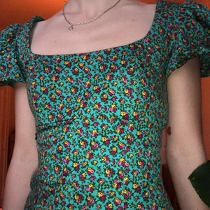 Drömmig sommarklänning! S - Världens drömmigaste sommarklänning!☀️ Både söt och cool. Grön med blommor och snörning i ryggen och puffiga ärmar. Slutar ovanför knäna. Jättebra skick!!🤝