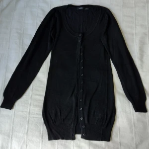 Svart stickad längre knäpptröja/kofta, storlek S 36/38 - Svart längre tunnstickad knäpptröja, storlek S 36/38. Passar XS/S, skulle jag säga. 100% viskos. Smånopprig/luden på vissa ställen..