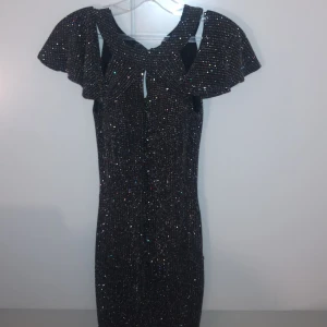 Fest Klänning - Glittrig Rygglös Off Shoulder Klänning med knytsnöre där bak. Finns Push Up I.  Klänning i fintskick. Användes en gång på Ny År. Storlek XS. Köptes för 1000kr, för 3 år sedan. 