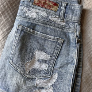 Lågmidjad kjol med coola detaljer på - Intressekoll på denna ursnygga vintage jeanskjolen! Så sjukt snyggt mönster/slitning på. Står på lappen att storleken är ”28” men skulle definitivt säga att den sitter som är normal S. Har inga bilder på då den är för liten tyvärr💕