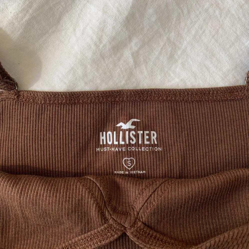 Oanvänt croppat brunt linne i storlek S från Hollister! Linnet har justerbara band! 🤎 Skriv privat för frågor eller fler bilder :). Toppar.