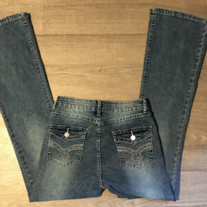 Lågmidjade jeans  - Säljer riktigt snygga jeans med detaljer på bakfickorna. Jeansen är utsvänga i benen och även lågmidjade. Säljs pga för små för mig. Hör gärna av dig för fler bilder! Köpt från Sellpy, ord pris 450 kr