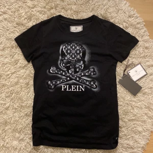 Philipp plein t-shirt - Har blivit för liten för mig men den är i jättebra skick inga rhinestone har lossnat. Har kvar tagsen som ni kan se på sista bilden och den kostade 1000kr ny på kidbrandstore.