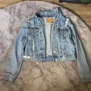  Ljusblå jeans jacka Med lite äfflade Hål lager 157 storlek xs  -  Använd fåtal gånger lite stel i materialet  