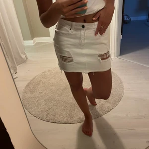 Vit jeanskjol  - Kort jeanskjol från Nelly. Väl använd i skicket. Strl är 38 men upplevs mer som 36. Töjs säkert ut 