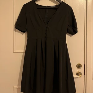 Svart klänning - En svart klänning med knappar vid urringningen. Helt oanvänd strl M