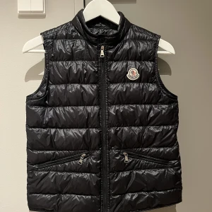 Moncler väst  - Säljer denna moncler väst då den har växt ut. Den har nu inte använts på 2 år men när jag köpte den växte den ut snabbt så han inte användas så mycket. Köptes 2018 och modellen heter ”moncler black gui down gillet. Storlek: 12/ 152 Skick: 9/10 