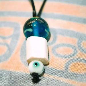 Halsband med ett hänge av trä, glas och porslin - Handgjort (av mig) halsband med ett hänge av trä, glas och porslin. Halsbandet har ett metallknäppe ”i nacken” för att passa alla huvudstorlekar. 💙🧿