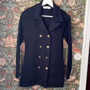 Busnel Victoria Jacket, Navy - Blazer i 100%  i ”navy” blå med åtta guldknappar och två fickor framtill. Mycket fint skick. 