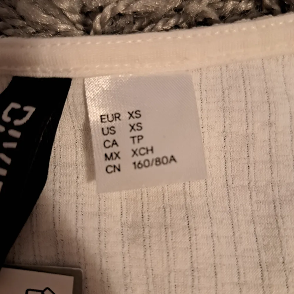 En oavänd t-shirt cardigan som fortfarande har kvar pristaggen. Köptes ifrån H&M men användes aldrig för att jag ångrade mitt köp. Toppen hålls ihop med metall fjärilen och går inte att öppna.  Obs! Köpare står för frakten. T-shirts.