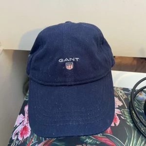 Mörkblå Gant keps  - Säljer nu min gant keps för jag har köpt ny.  Den är i bra skick men den drar väldigt enkelt åt sig ludd.  One size 