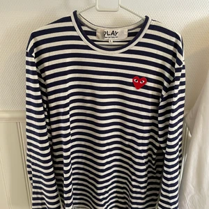 CDG ”Commes des garcons play” - En långärmad CDG tröja i storlek L. Cond avgör själva, finns ett litet hål på tröjan som ses i bilden bak på tröjan. Vid frågor och funderingar är det bara att skriva.