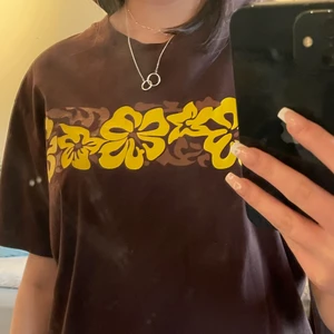 brun T-shirt med blommor - En jätte fin t shirt med blommor på bröstet, köpt second hand 