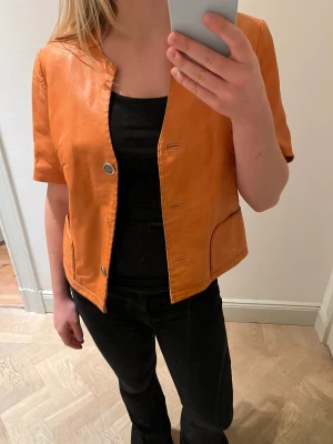 Läderkavaj  - Så häftig läderkavaj med korta ärmar i orange🧡Den är i äkta läder och inköpt på Humana vid Mariatorget! Tyvärr saknas en knapp, därav det låga priset😰