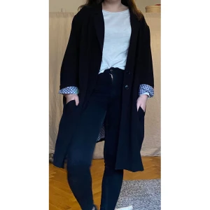 Svart kappa, snygg oversized - Fin svart kappa, relativt tunn. Storlek 52 men supersnygg som oversized. Jag är 170 cm och vanligtvis 38/40 för referens. Ärmarna är upprullade på bilden då de är lite för långa, nedvecklade är ärmarna helt svarta.