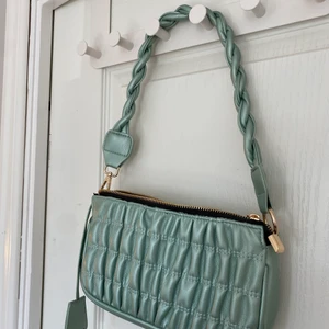 Glitterfärgad ljusgrön axelremsväska  - Aldrig använd. Nyskick och superfin. Från Nelly, märket ”glamorous”. Passar perfekt till festligare sammanhang 🥰 ordinarie pris 349kr men verkar inte säljas längre!