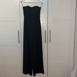 Jumpsuit  - Elegant fin jumpsuit med citatet topp utan armar och utsvängda i längden, helt oanvänd! 