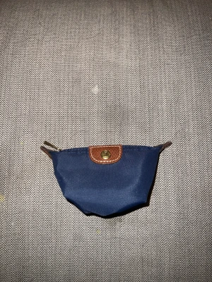 Longchamp plånbok  - En plånbok/mynthållare från longchamp, perfekt att ha mynt i o kanske ett kort oxå ( har inte testat )  Superbra skick, inga fläckar eller märken och knappt använd. Möjligen 2-3 år gammal 