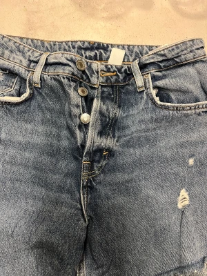Jeans med hål - Ett par jeans från H&M. Hål med tyglappar bakom, lite använda men fint skick. Storlek 36 