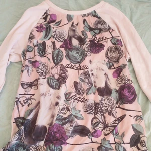 H&M ljusrosa tröja  - En H&M ljusrosa tröja med blommösnster på framsidan, ljusrosa baksida, och spets längst ner. Strl 170 barn.  
