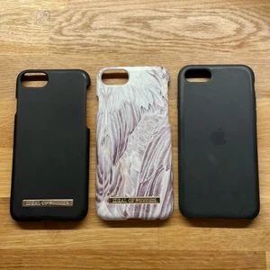 Skal till IPhone 7,8  - Tre stycken iPhoneskal till 7 och 8. Två från ideal of Sweden och ett från Apple. De svarta skalen ser mer använda ut. Det vita med fjädrar är i bättre skick. Alla för 100 eller 50kr/st.