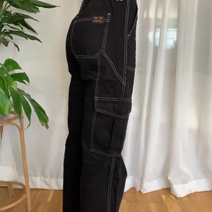 Cargobyxor från urban outfitters  - Cargopants i mycket bra skick. Svarta med vita sömmar från Urban Outfitters. Stretch i midjan så passar XS-M.
