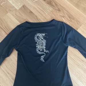 Svart tröja med glittrig drake - Säljer denna fina tröja med en glittrig drake från humana! Armarna går till lite under armbågen. Köpt för 190kr