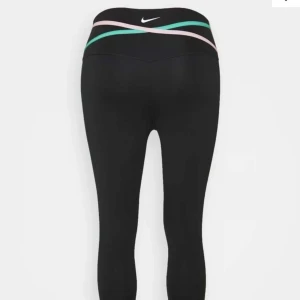 Träningstights från Nike - Svarta träningstights från Nike med detalj med färgerna grön och rosa. Använda ca 3 gånger. Ny pris 650.