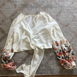 Knytblus  - En vit croppad knytblus med långa mönstrade ärmar med en v urringning. Från SHEIN. Skickas via post eller möts upp :)