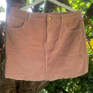 Rosa manchesterkjol strl.40 - Kort kjol i manchester från Ginatricot, gammalrosa i färgen och storlek 40. Har hållare för skärp och fickor fram.