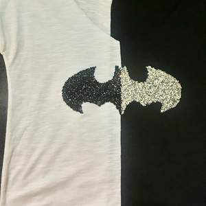 En tröja som är hälften vit och den andra hälften svart, med Batman skylten på