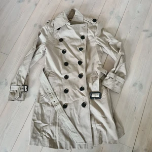 Trenchcoat stl 36 i nyskick!  - Säljer en jätte fin beige trenchcoat i stl 36 som jag bara använt 2 ggr. Skärp runt midjan samt burberry foder inuti. Väldigt fin!