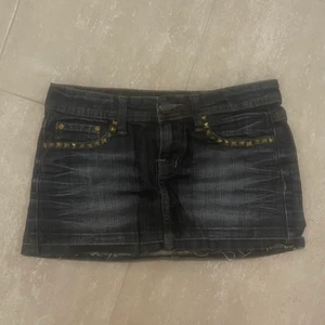 Lågmidjade jeans kjol  - Mörk blå jeans kjol med guldiga nitar vid fickorna. Typ aldrig använd så är som ny!