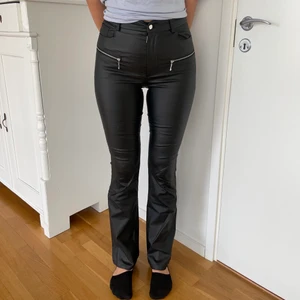 Skinnbyxor - Byxor i läderimitation från NAKD - AFJ kollektion. Fina dragkedjor fram, fickor bak och utsvängda ben. Storleken är 38 och jag är 178cm lång 