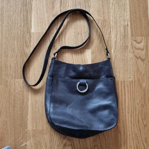 Liten svart väska - Liten svart väska i syntetmaterial, ca 23x19 cm. Aldrig använd.