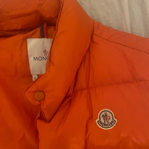 Moncler väst - Säljer nu denna as snygga orangea moncler västen!❤️💕  Äkta såklart, är bara en äldre modell!💕 Har brist på äktahetsbeis där av det låga priset!❤️ Möts upp i Stockholm helst!❤️💕