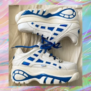 Fräna buffalo-skor med platå 😌 - Spejsiga skor från Buffalo. Jag har köpt dessa via Tradera för några år sedan så jag har tyvärr inte mer information än vad bilderna visar - skorna är vita med blå detaljer, storlek 41. De förtjänar kärlek jag inte kan ge dem 💔 jag ansvarar inte för postens slarv. De väger strax över 1,5kg, därför är frakten dyr, men det är det värt! Kan även mötas i Malmö.