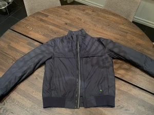 Hugo boss jacka  - Säljer åt en kompis! Superfin vårjacka/vindjacka, helt oanvänd! Från Hugo boss storleken står ej men skulle uppskattas till L/M. Marinblå färg med gröna detaljer! ☺️