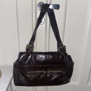 Brun vintage väska  - Jättefin brun vintage väska. Köpt på second hand. Använt, men bra skick. Älskar den men har för många väskor därav säljer jag den. Väldigt rymlig. 35cm bred, 18 cm hög🤎