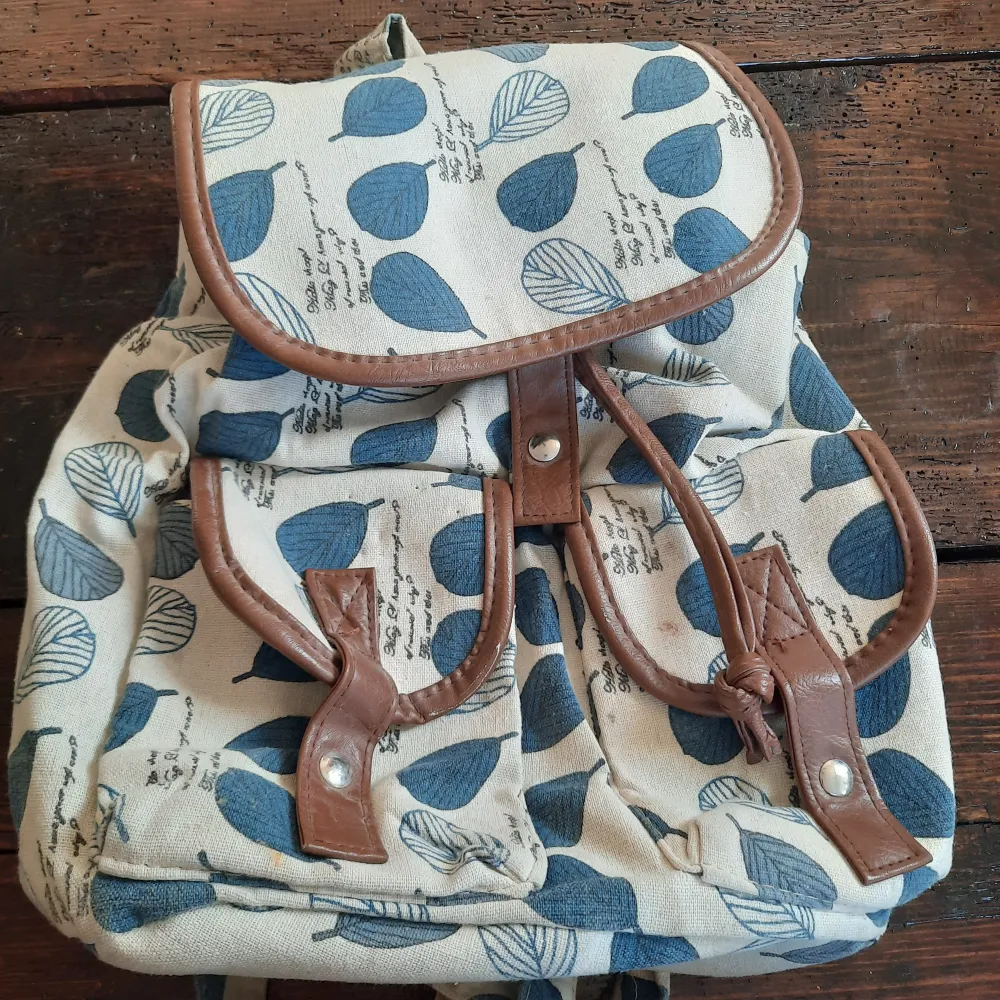 Snygg tyg ryggsäck med läder och blåa blad detaljer. . Väskor.