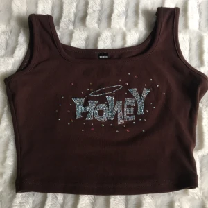 Honey Top/linne - En brun honey top från shein🤎 Saknas en sten (som du ser på bilden) Den är i storlek XS💕 Jag säljer den för att jag inte använt den så mycket.  Tar endast swish, skriv vi intresse🥰