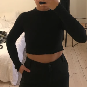 Svart ribbad kort polo från Monki - Svart ribbad croppad polo från Monki. Fina volangdetaljer i kanterna 🤍 Sparsamt använd, i fint skick!