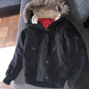 Lumberjacka stl 34 /36 svart med luva och pälskant . - Lumberjacka stl 34 /36 med luva och pälskant och knäppes med dragkedja och knappar fram samt fickor .fint skick .hämtas i Skene alt skickas o köpare betalar frakten o Swishbetalning tillämpas .frakt inräknat i priset .(104 ).