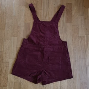 Hängselbyxor strl S-M - Hängselshorts i vinröd manchester, storlek 38, ca 82cm i midjan. Hängslena går att justera med knappar, se sista bilden Två små fickor på framsidan, dragkedja i sidan. Tröjan jag har till är också till salu, se i profil. 