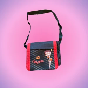 Axelremsväska tryck - Så cool axelremsväska med tryck (Betty Boop) i perfekt skick😍 Datorn får absolut plats, bandet är justerbart och den har många bra fack! Kan mäta hur stor väskan är exakt om ngn är intresserad:) Priset kan diskuteras! Skriv privat vid intresse o frågor💋💋