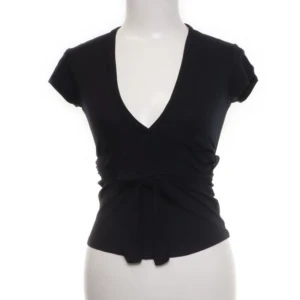 Öppen rygg topp - Svart, halv elastisk topp i skönt material med snöre vid midjan. Formar kroppen fint. Köpt second hand, säljer pågrund av för mycket kläder 